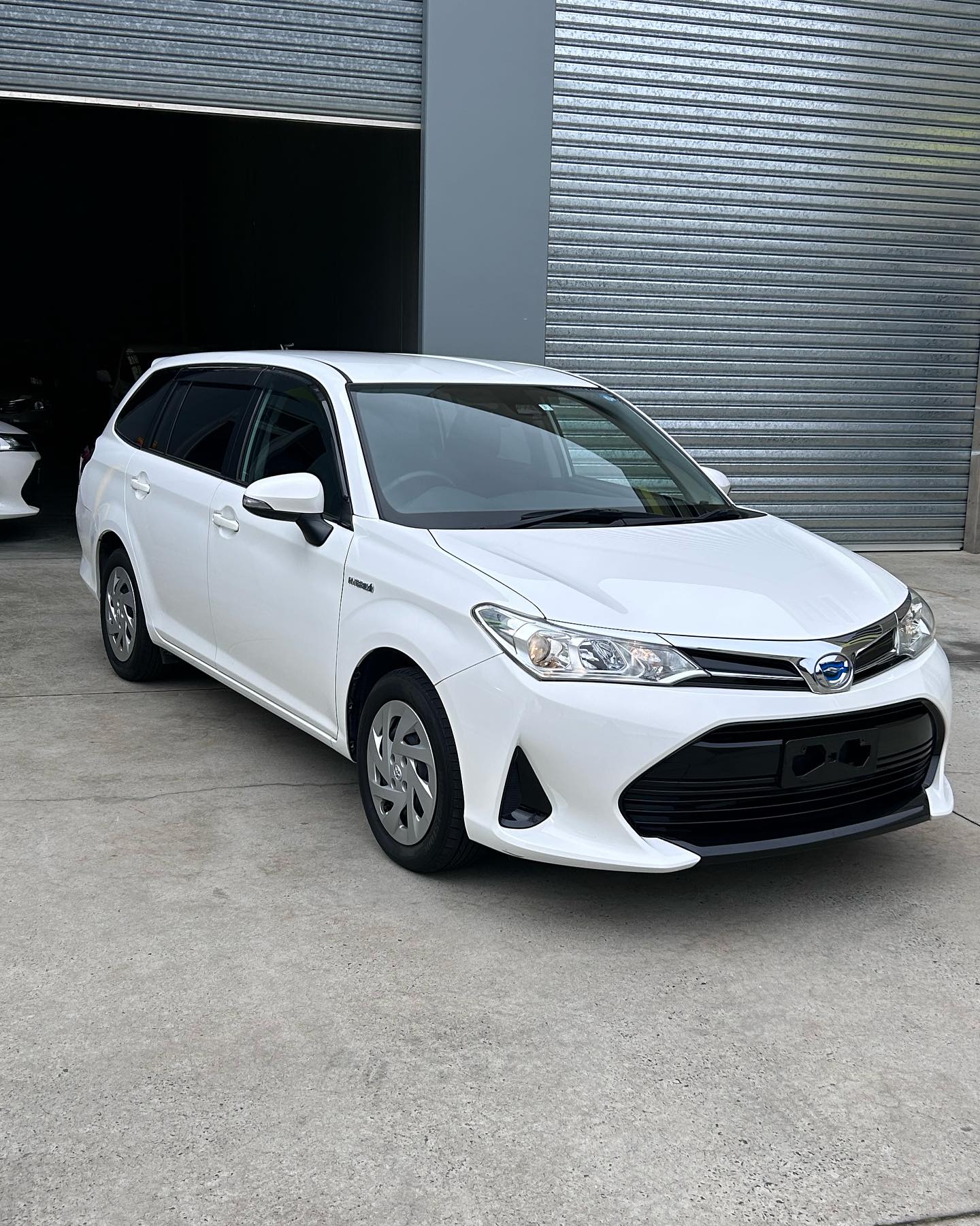 White Toyota Corolla parked in front of garage.